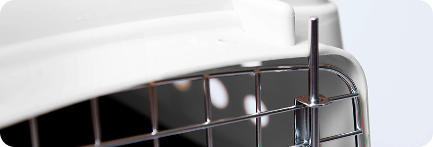 A close-up of the metal wire door of a pet carrier, showing a locking pin.